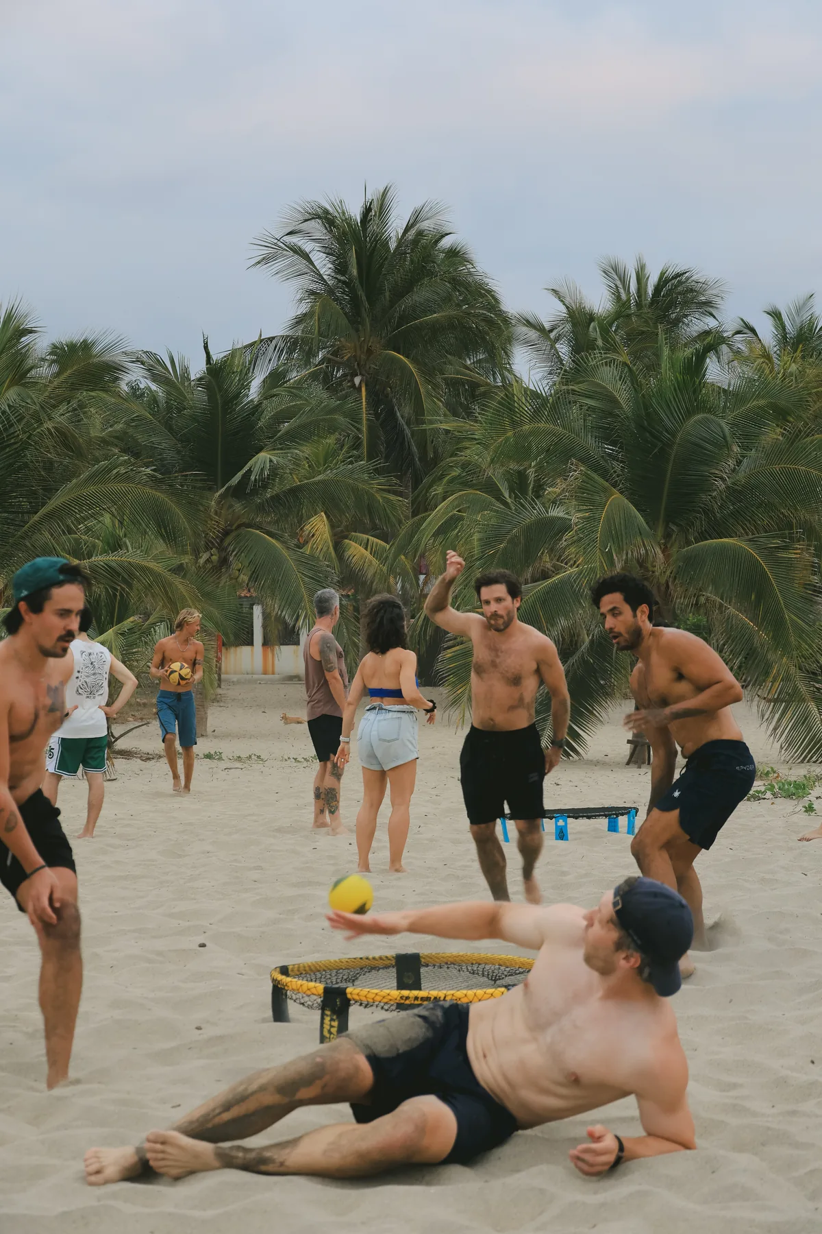 Guests playing spikeball on the beach beneath the palms near La Punta, Puerto Escondido