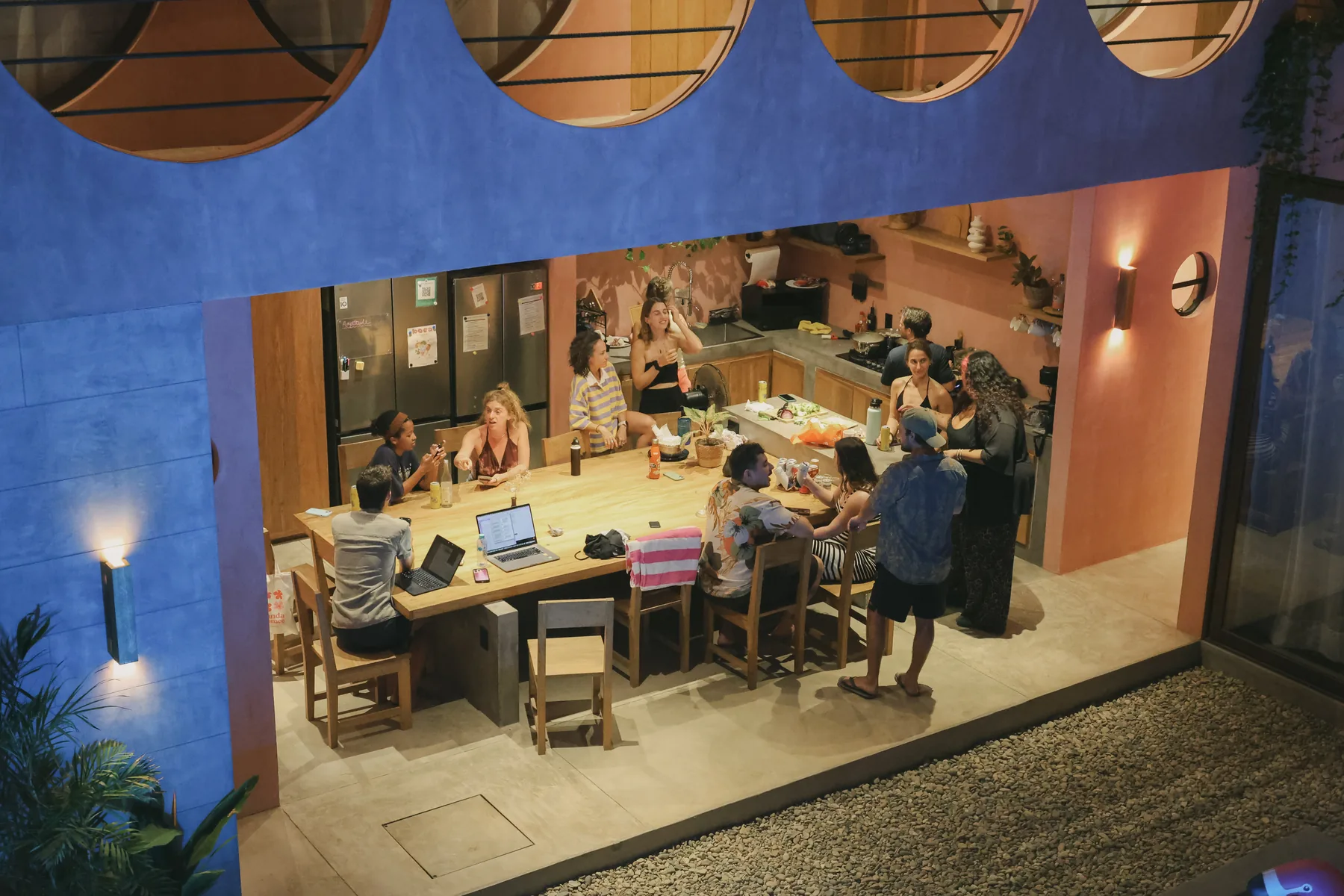 Guests gathered around the communal table for a community dinner in the open-air kitchen at Amplitude Coliving, La Punta