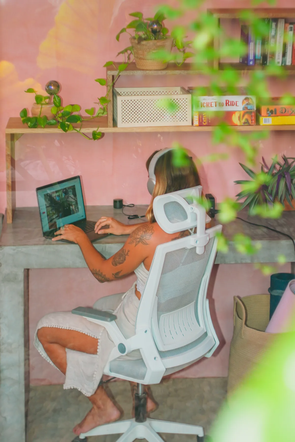 A guest on a video call at an ergonomic desk in the plant-filled coworking space at Amplitude Coliving, La Punta