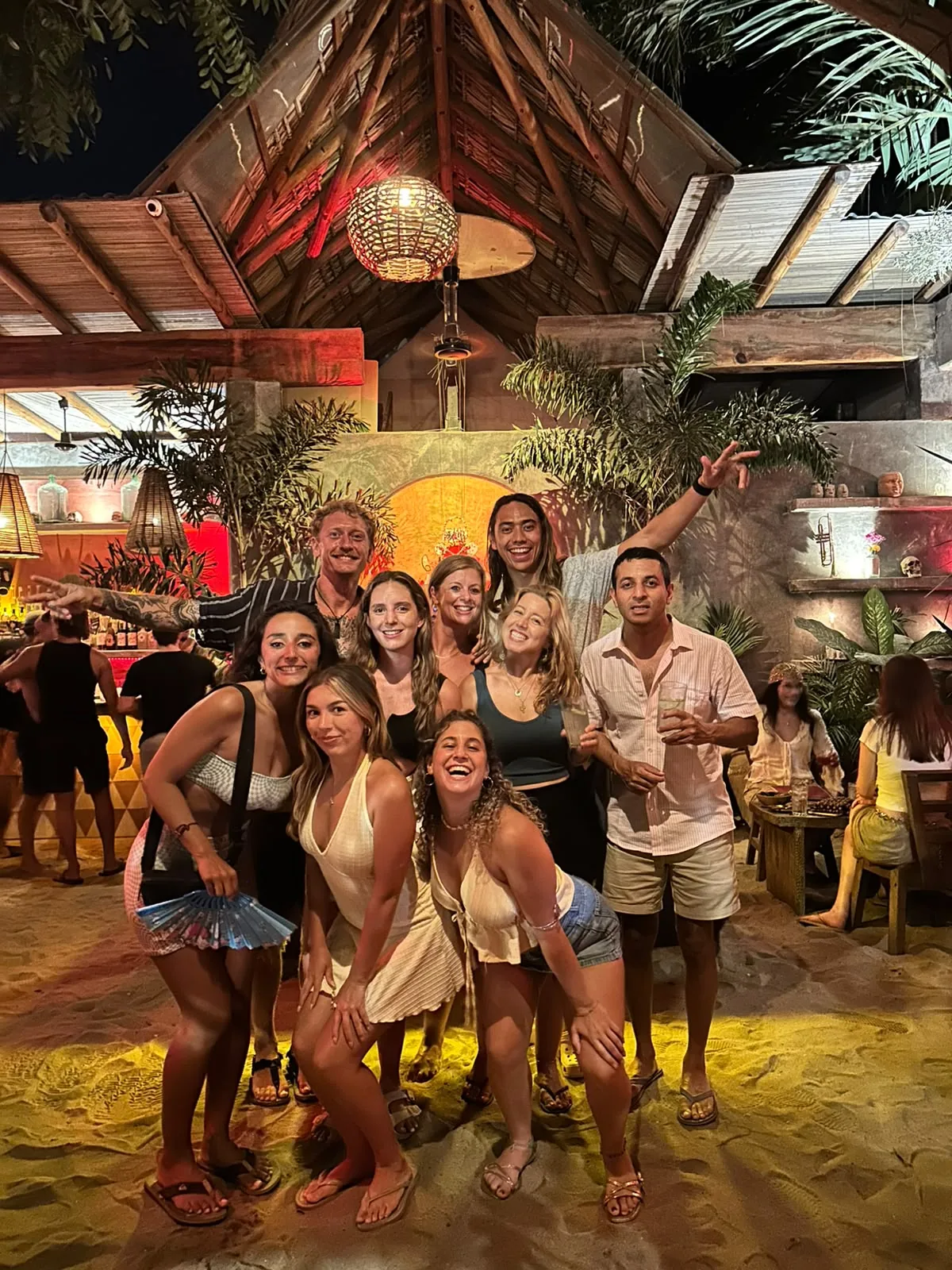 Guests posing together at a tropical beach bar at night in La Punta, Puerto Escondido