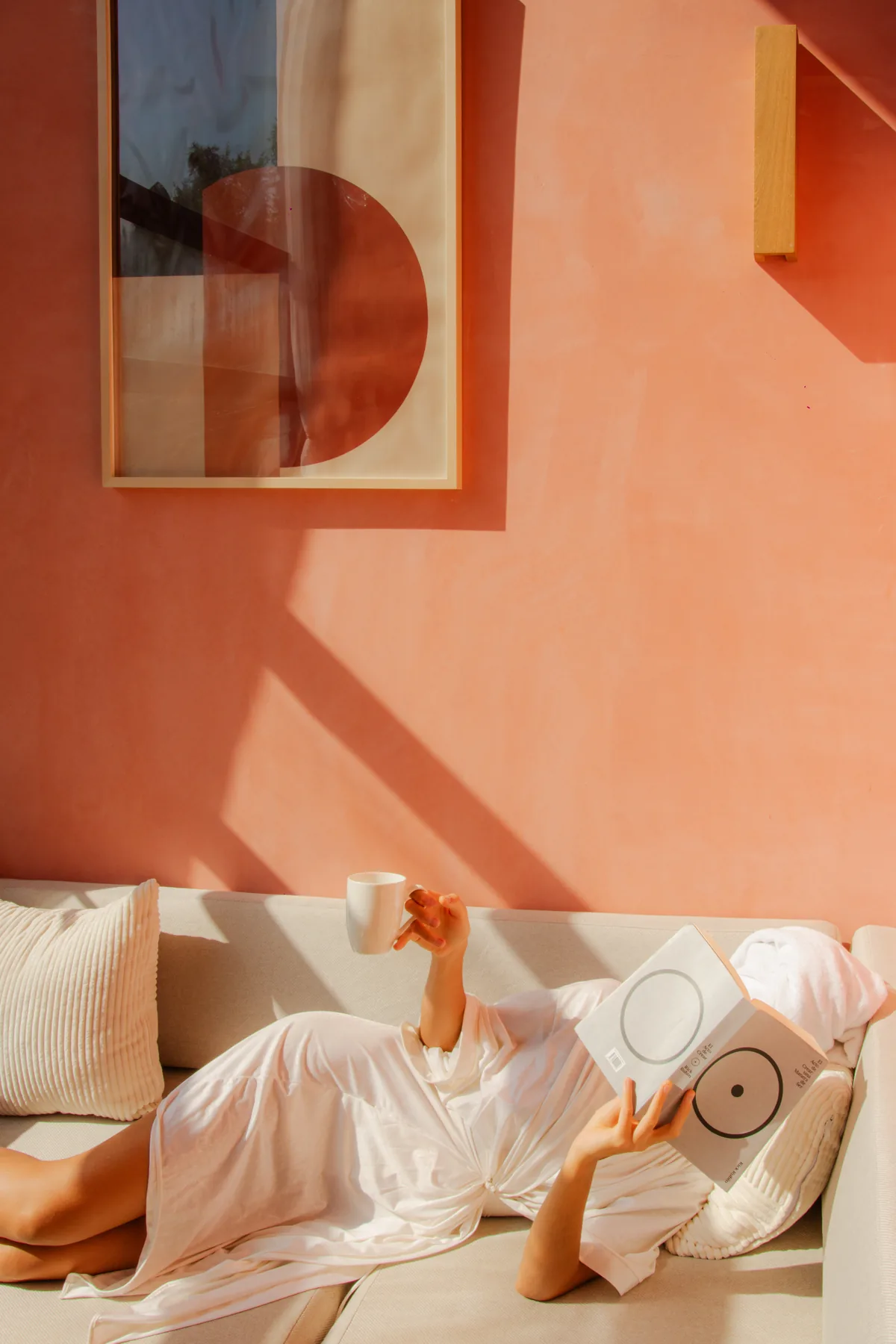 A guest relaxing on a sofa with coffee and a magazine in warm afternoon light at Amplitude Coliving, La Punta