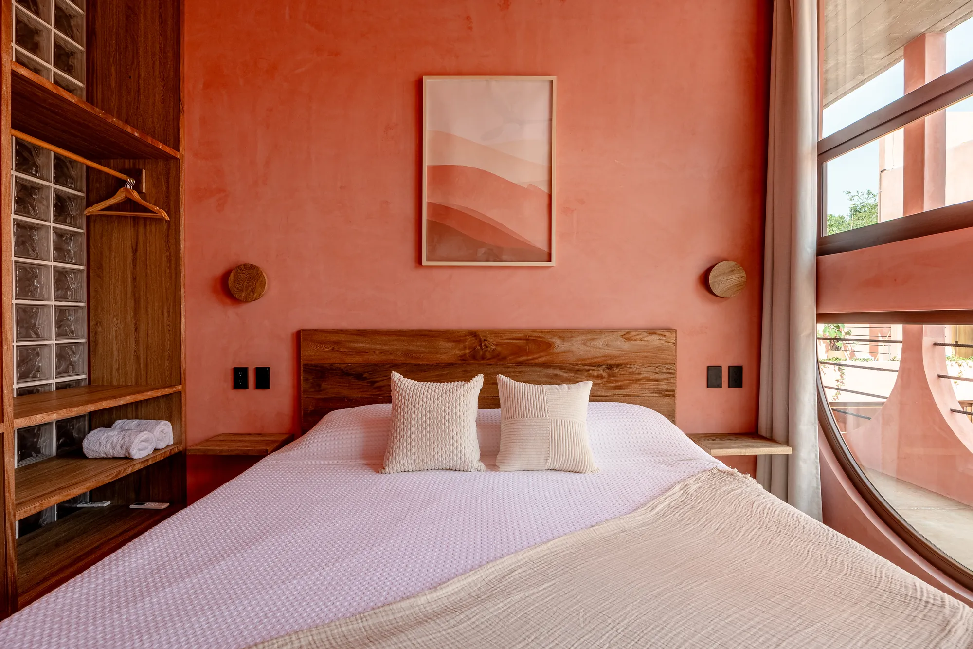King bed beneath an arched window at Amplitude Coliving in La Punta
