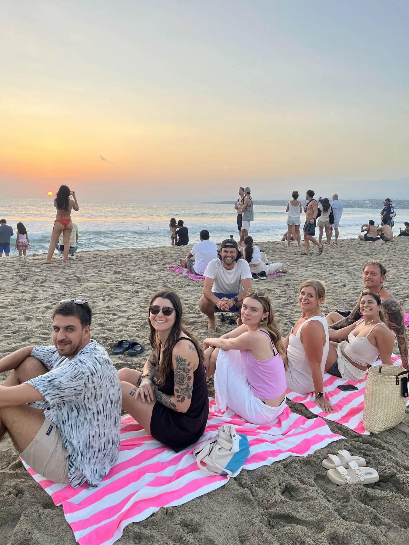Guests watching the sunset from the beach on striped towels at La Punta, Puerto Escondido