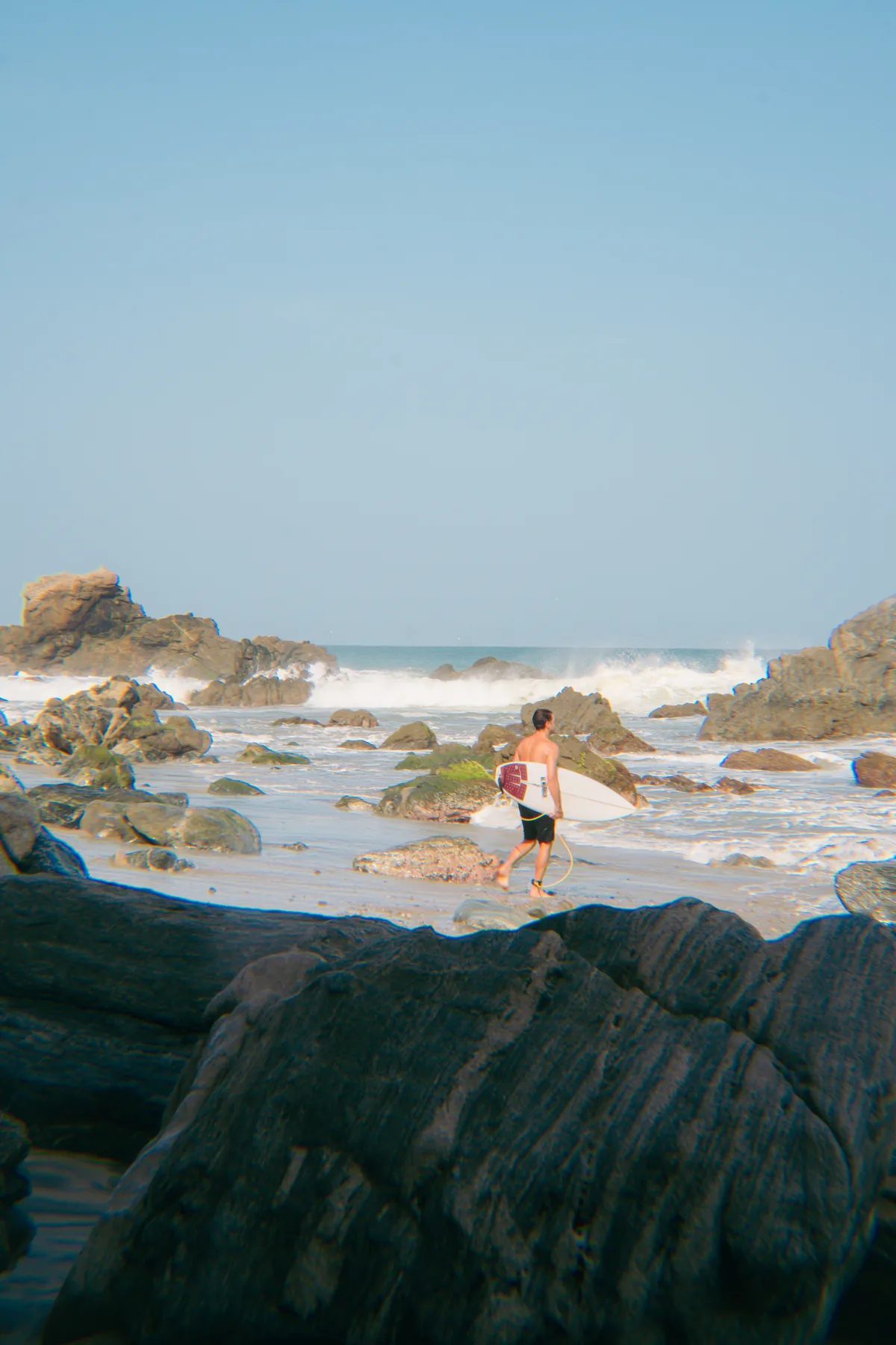 A surfer walking to the world-class break at La Punta, a four-minute walk from Amplitude Coliving in Puerto Escondido