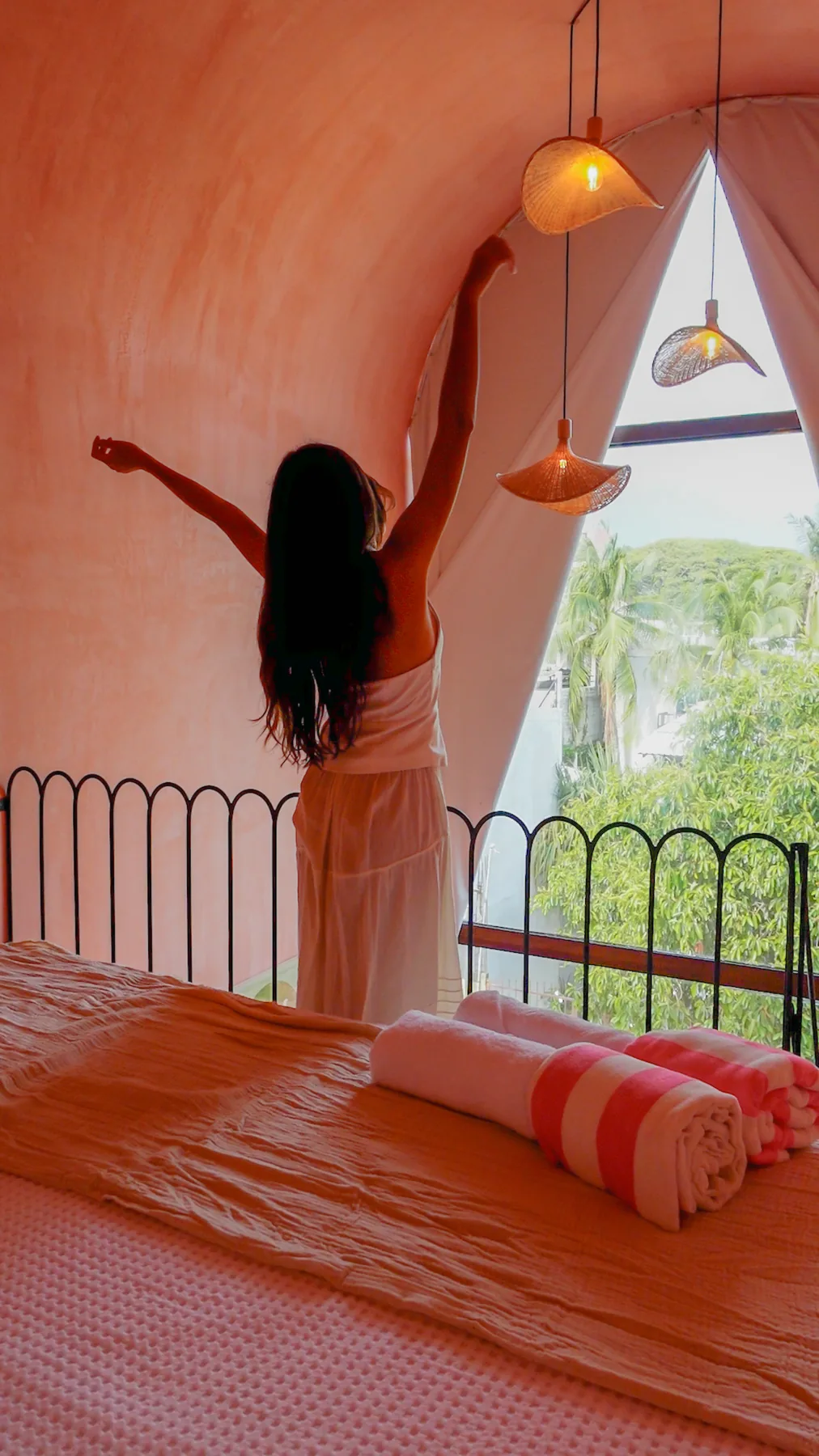 A guest stretching by the arched window of a loft room in the morning light at Amplitude Coliving, La Punta